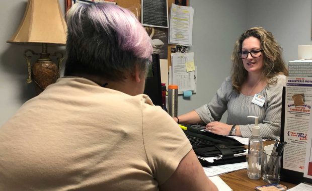 A woman seeking financial assistance sits across the desk from a caseworker during an interview for assistance.