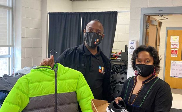Phillip Miller holds a bright new coat with Raukell Robinson holding new shoes for CMS students.